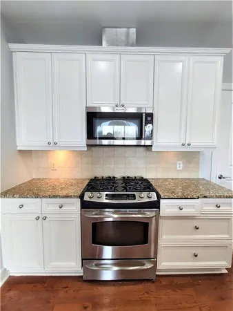 a kitchen with granite countertop white cabinets and stainless steel appliances
