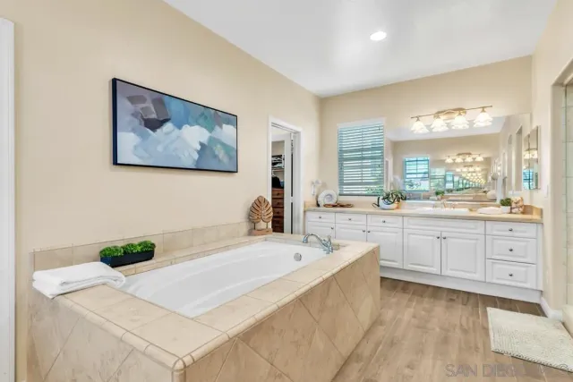 a spacious bathroom with a tub a double vanity sink and a window