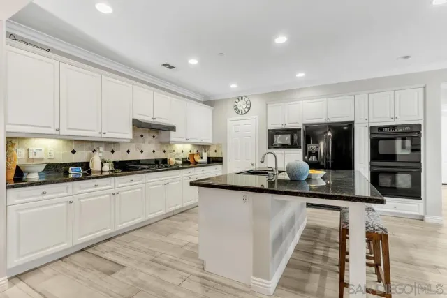 a kitchen with kitchen island granite countertop a sink counter top space appliances and cabinets
