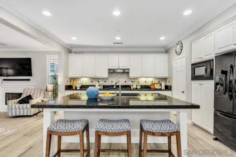 a kitchen with stainless steel appliances granite countertop a stove top oven a refrigerator a sink a dining table and chairs