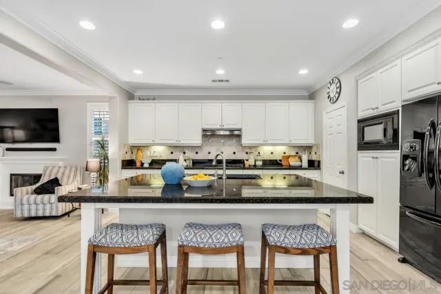 a kitchen with stainless steel appliances granite countertop a stove top oven a refrigerator a sink a dining table and chairs