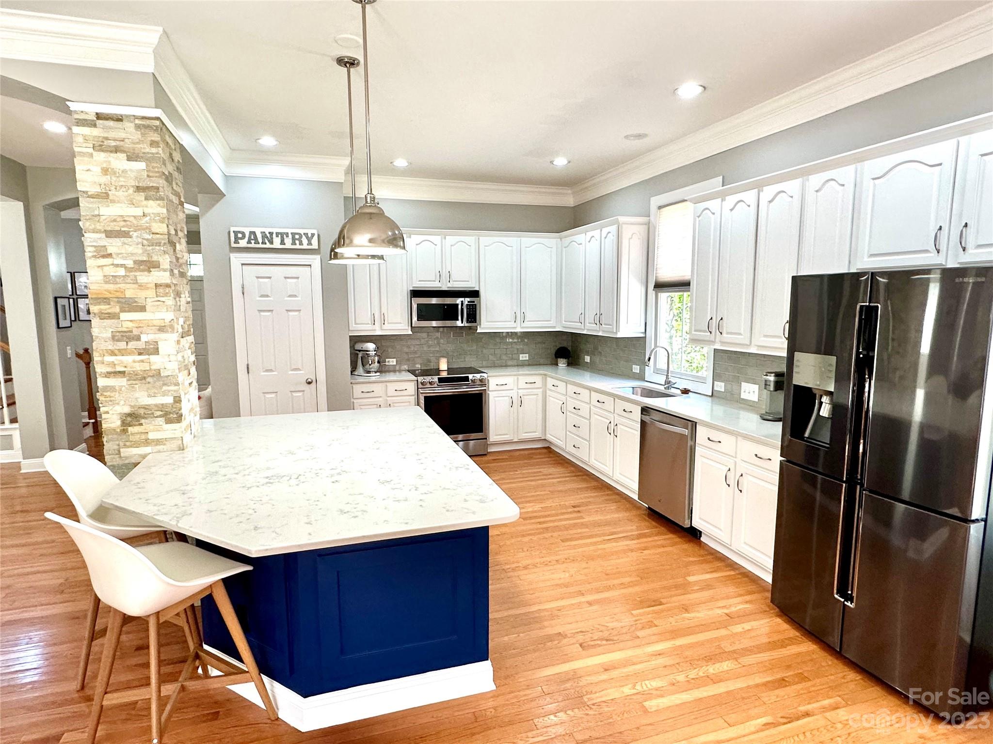 7112 Michael Scott Crossing Fort Mill, SC 29708 - Photo 8 of 48 a kitchen with stainless steel appliances kitchen island granite countertop a refrigerator a sink dishwasher a stove with white cabinets and wooden floor