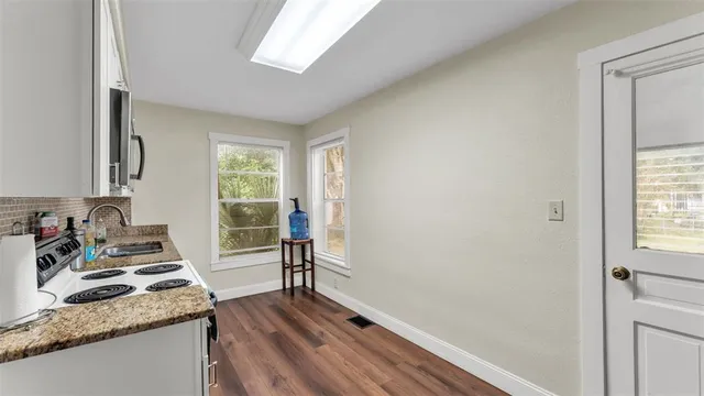 a kitchen with granite countertop a stove a sink and a refrigerator