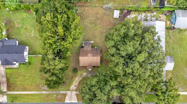 an aerial view of a house with a yard and large trees