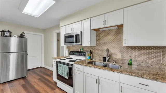 a kitchen with granite countertop a sink a counter space stainless steel appliances and cabinets