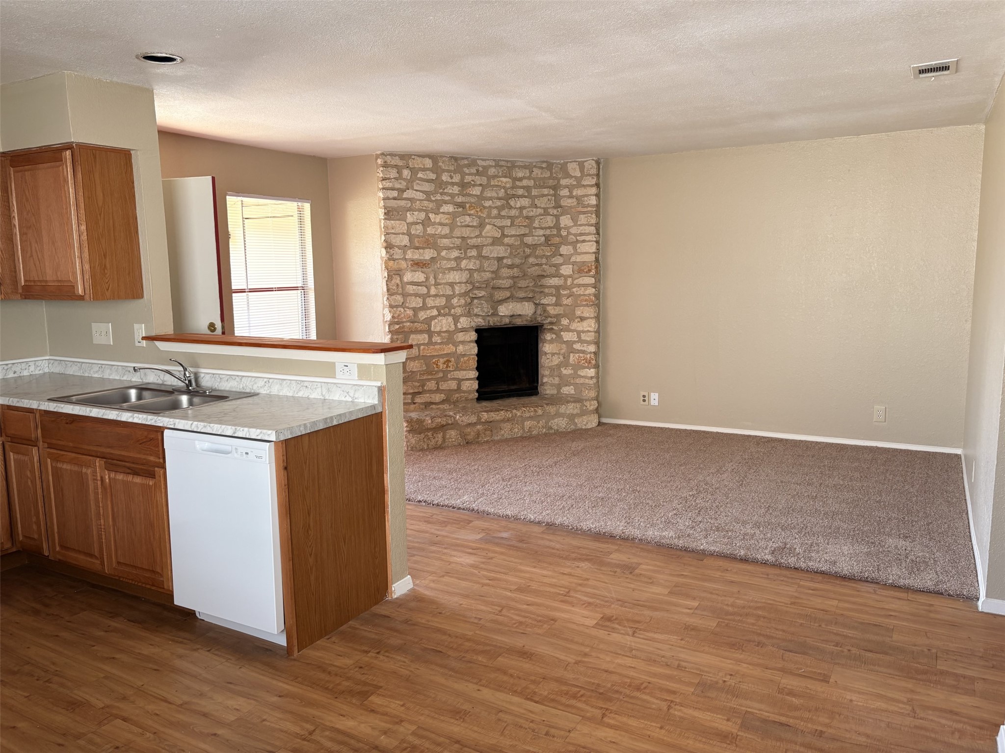 9902 Roxanna Drive, Unit D Austin, TX 78748 - Photo 19 of 19 Kitchen featuring white dishwasher, open floor plan, wood finish cabinets, light countertops, and a large fireplace