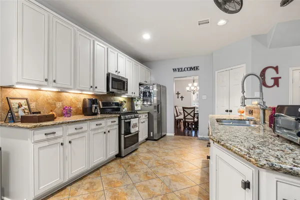 a kitchen with kitchen island granite countertop a stove sink and cabinets