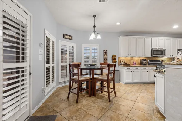 a kitchen with kitchen island granite countertop a stove a sink a dining table and chairs