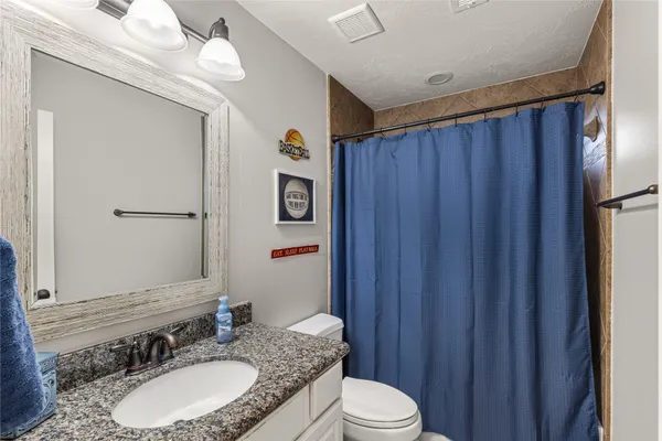 a bathroom with a granite countertop sink vanity mirror and toilet