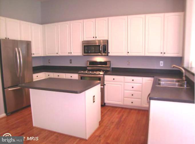 a kitchen with granite countertop a sink a stove and refrigerator