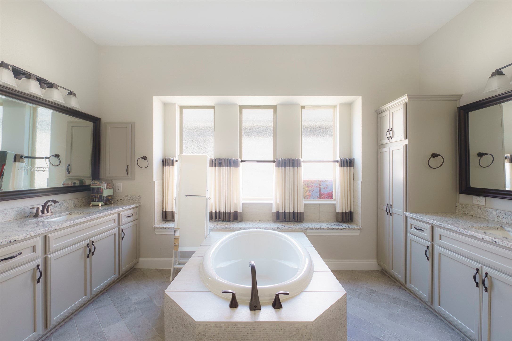2305 Millbrook Loop Leander, TX 78641 - Photo 18 of 26 A well-lit primary bathroom featuring dual vanities, granite counters, and a freestanding soaking tub.