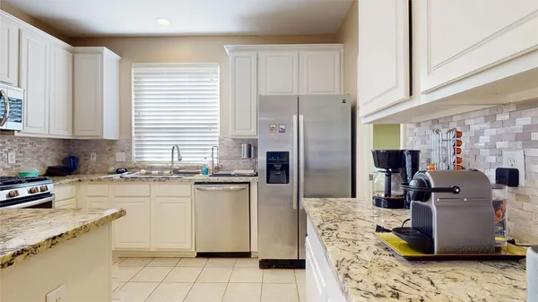 a kitchen with stainless steel appliances granite countertop a refrigerator a stove a sink and white cabinets