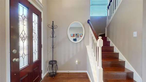 a view of a hallway with front door wooden floor and stairs