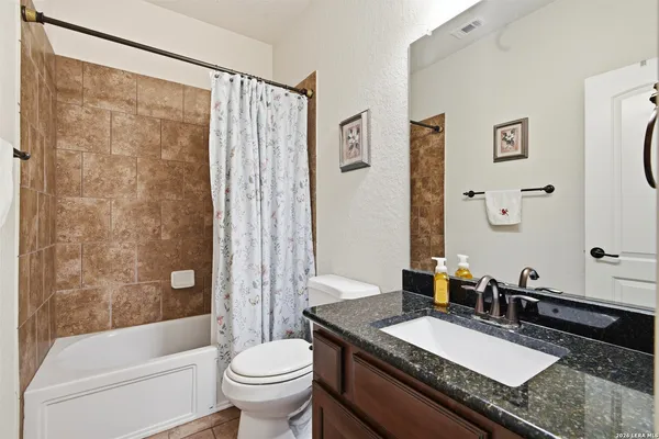 a bathroom with a granite countertop sink toilet a mirror a bathtub and shower