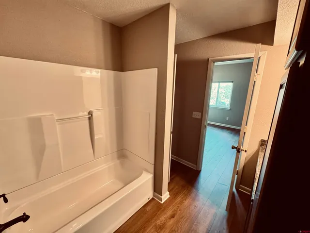 an empty room with wooden floor and a ceiling fan