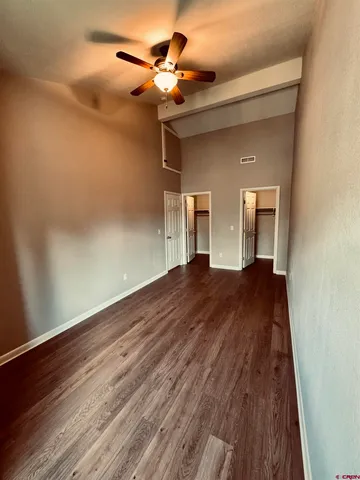 an empty room with wooden floor fan and windows