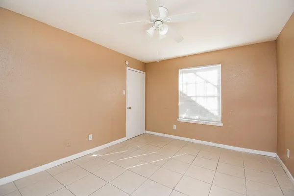 an empty room with windows and fan