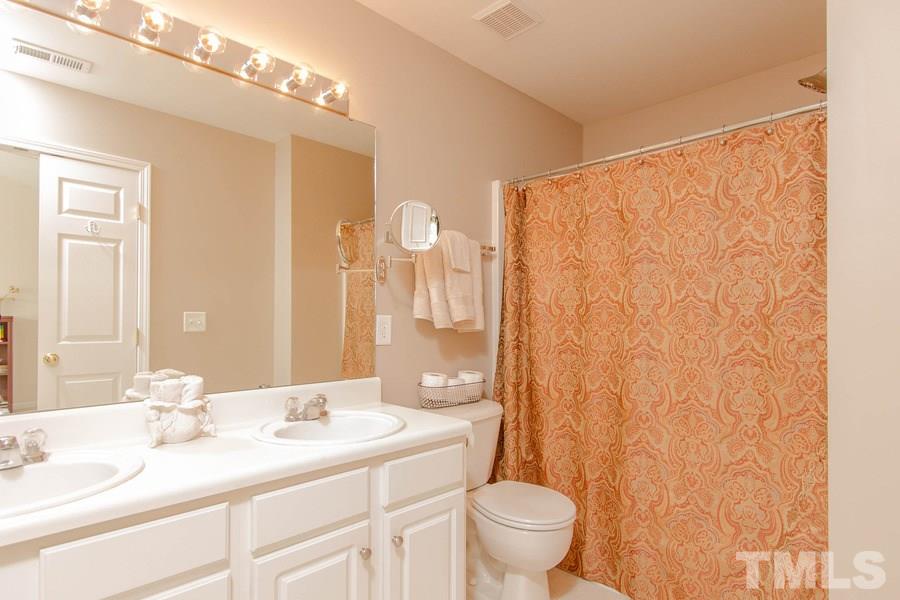 8147 Rhiannon Road Raleigh, NC 27613 - Photo 11 of 19 a bathroom with a granite countertop sink a toilet and a mirror
