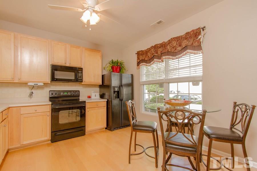 8147 Rhiannon Road Raleigh, NC 27613 - Photo 4 of 19 a kitchen with a stove a refrigerator and chairs