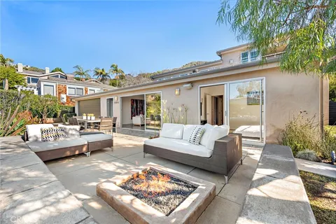 a view of a patio with couches table and chairs with potted plants and big yard