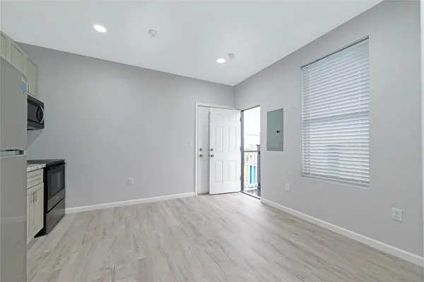 a view of an empty room with wooden floor and a window