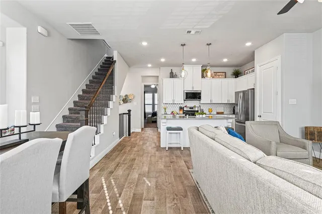 a kitchen with stainless steel appliances kitchen island granite countertop a stove a sink a refrigerator and white cabinets with wooden floor