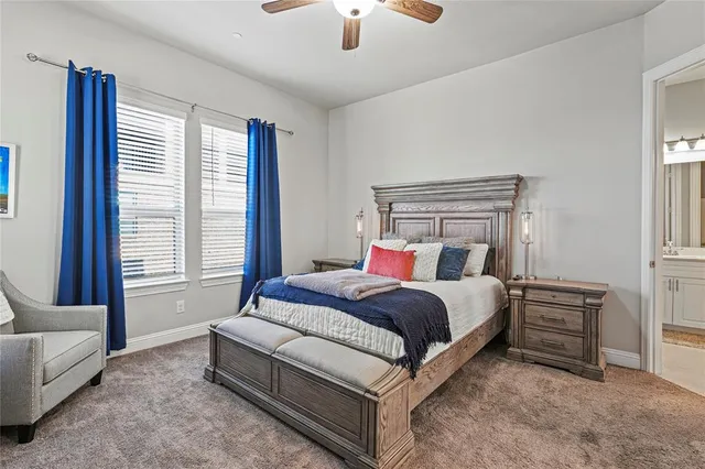a spacious bedroom with a bed a couch and a chandelier fan