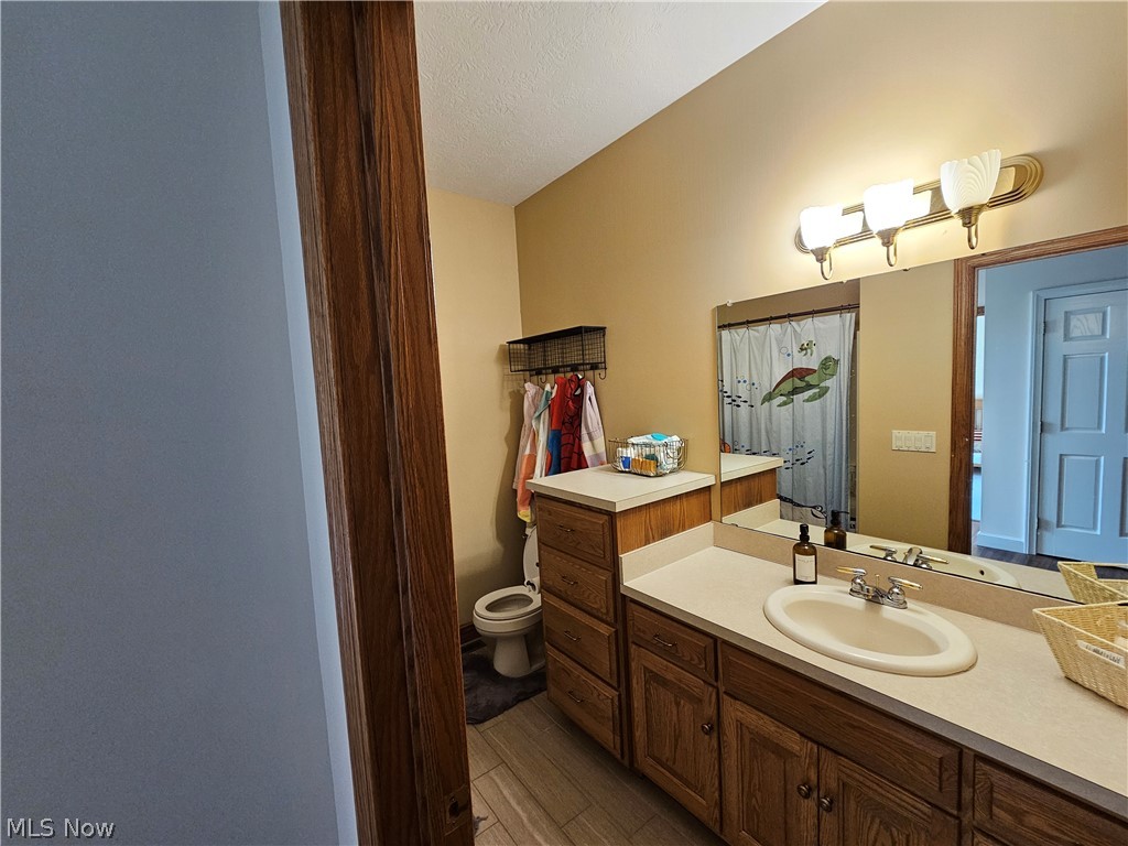 2363 Tabor Ridge Road Northeast New Philadelphia, OH 44663 - Photo 23 of 42 Bathroom vanity featuring a light-colored countertop, an undermount sink with a chrome faucet, and wood-finish cabinetry