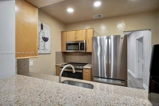 a kitchen with granite countertop a refrigerator and a sink