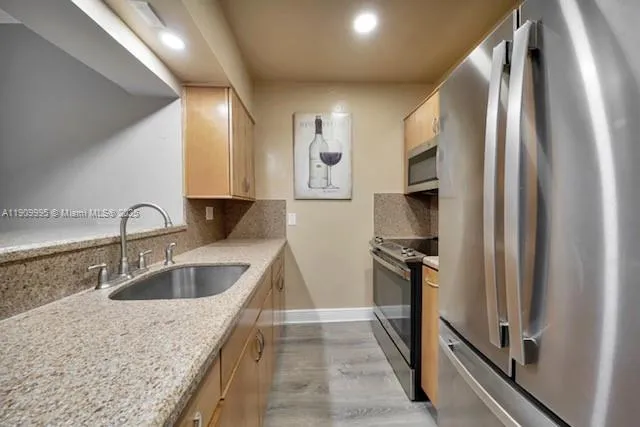 a kitchen with stainless steel appliances granite countertop a refrigerator and a sink