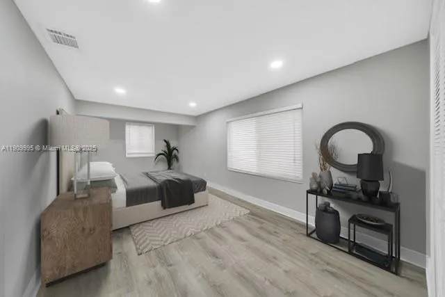 a spacious bedroom with a bed a dresser and wooden floor