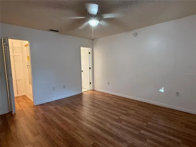 an empty room with wooden floor and windows
