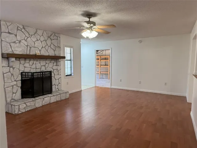 a view of an empty room with wooden floor and fireplace