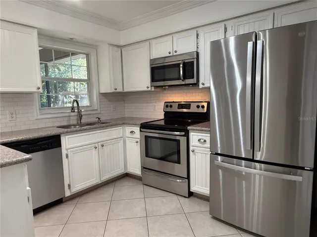 a kitchen with cabinets stainless steel appliances and window