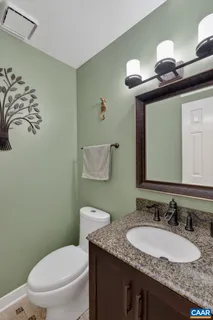 a bathroom with a granite countertop toilet a sink and a mirror