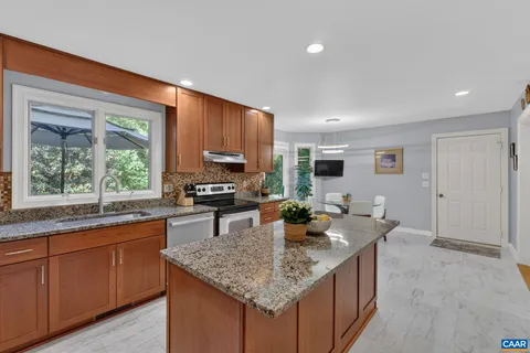 a kitchen with kitchen island granite countertop a sink counter and chairs