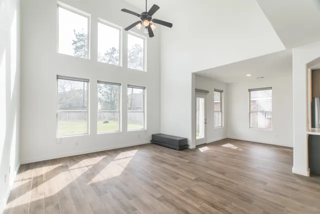 a view of empty room with wooden floor and fan