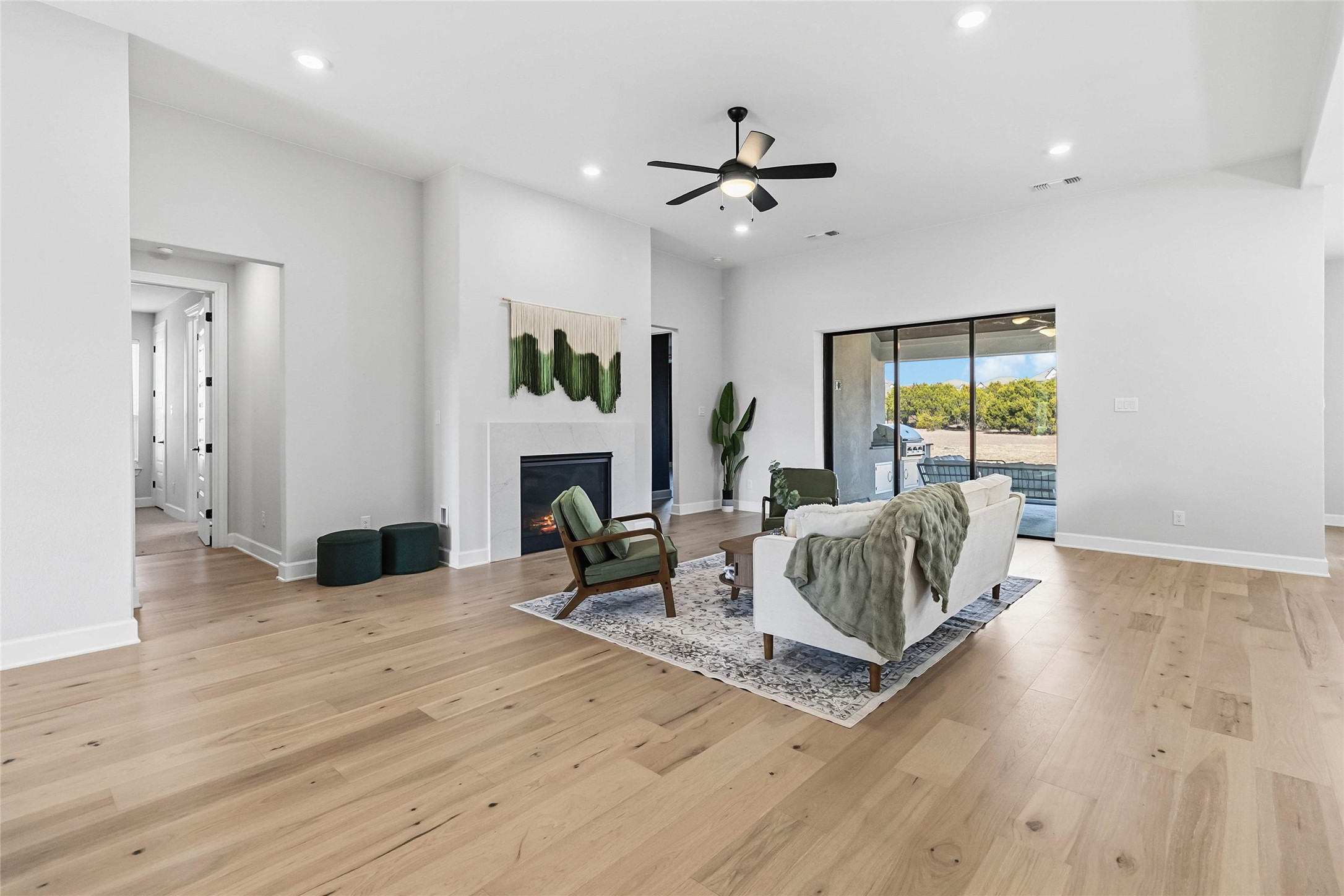 640 Prairie Clover Drive Dripping Springs, TX 78620 - Photo 3 of 32 Living room featuring light wood-type flooring, recessed lighting, ceiling fan, and a glass covered fireplace