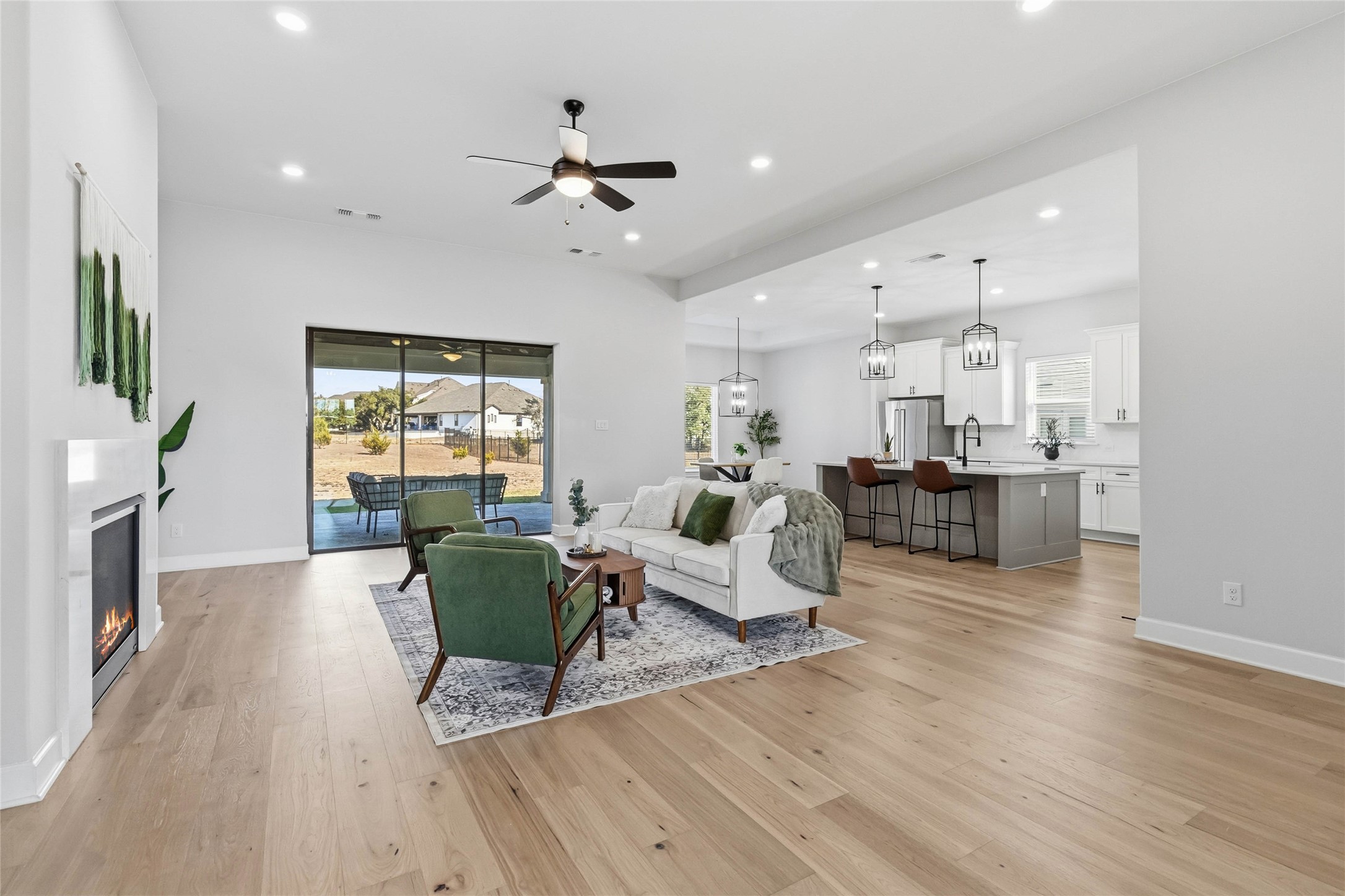 640 Prairie Clover Drive Dripping Springs, TX 78620 - Photo 5 of 32 Living room featuring plenty of natural light, a glass covered fireplace, recessed lighting, ceiling fan, and light wood-style floors
