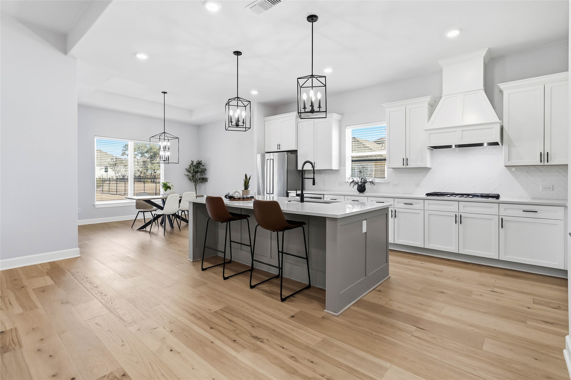 640 Prairie Clover Drive Dripping Springs, TX 78620 - Photo 7 of 32 Kitchen with a breakfast bar area, a center island with sink, decorative light fixtures, white cabinetry, and recessed lighting