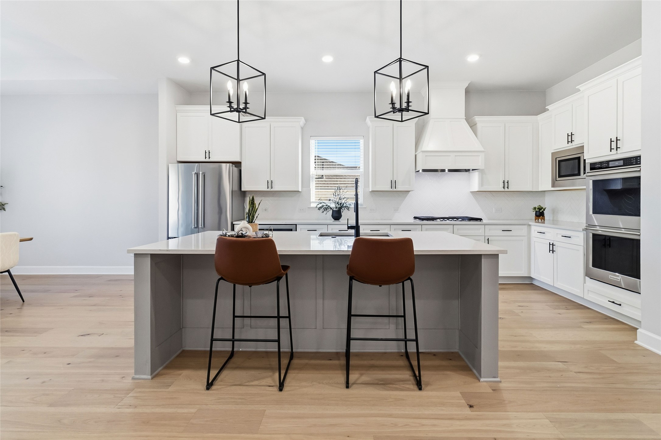 640 Prairie Clover Drive Dripping Springs, TX 78620 - Photo 8 of 32 Kitchen with a center island with sink, a kitchen breakfast bar, decorative light fixtures, stainless steel appliances, and light wood-style flooring
