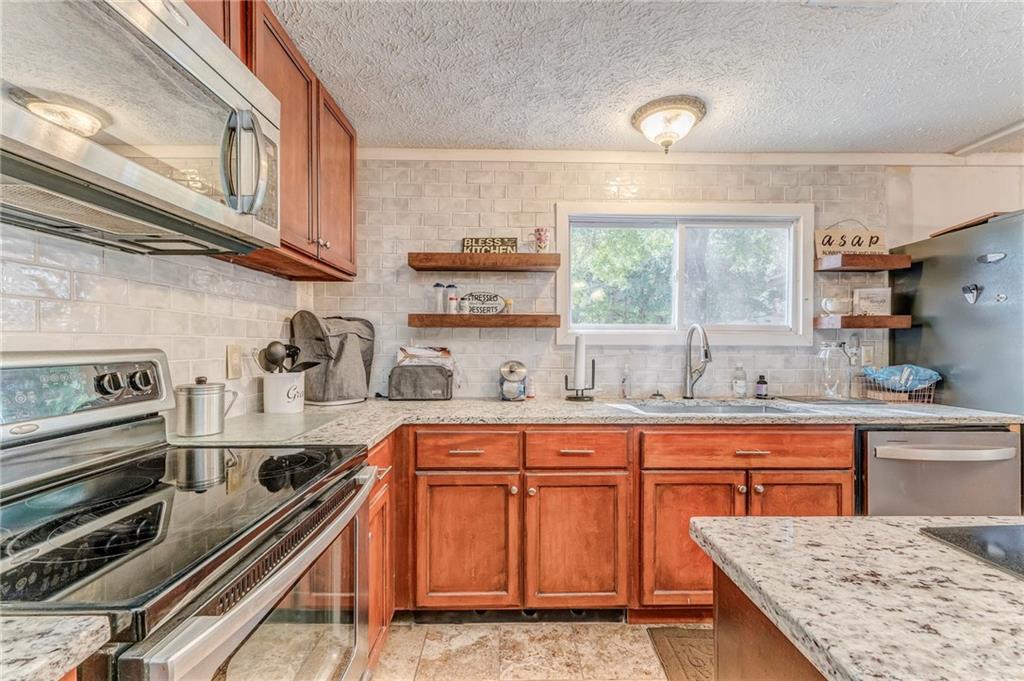1039 Old Cedartown Road Rockmart, GA 30153 - Photo 25 of 40 a kitchen with stainless steel appliances granite countertop a stove a sink and cabinets
