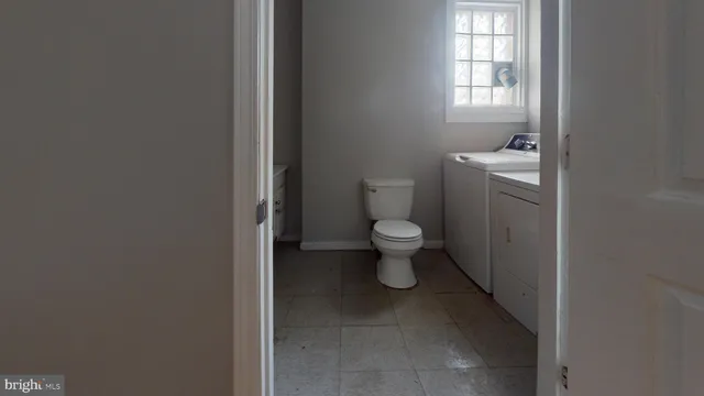 a bathroom with a toilet sink a window and vanity