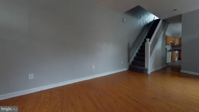 an empty room with stairs and wooden floor