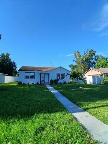 a view of a big house with a big yard plants and large trees