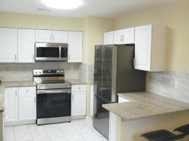 a kitchen with granite countertop a refrigerator and a stove