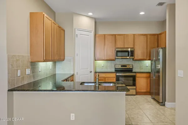 a kitchen with stainless steel appliances granite countertop a refrigerator a stove and a sink