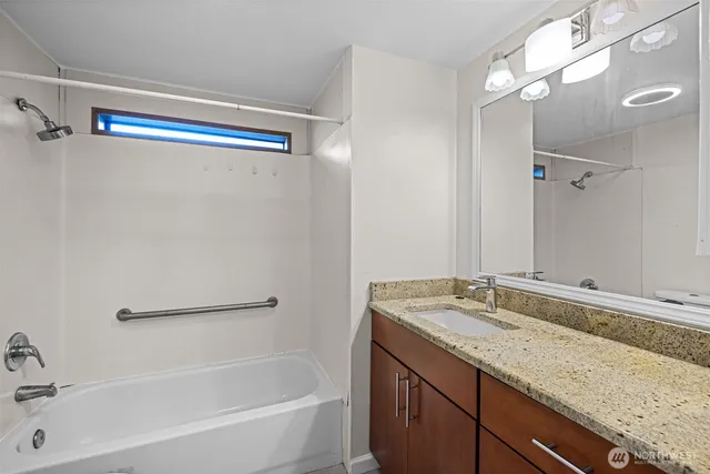 a bathroom with a granite countertop sink a mirror and a bathtub