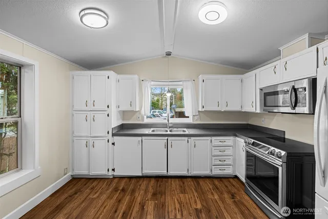 a kitchen with granite countertop a stove a sink and dishwasher with white cabinets