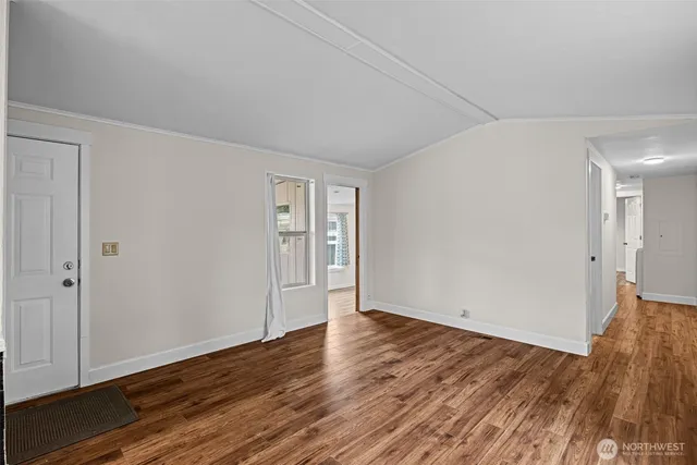 a view of an empty room with wooden floor and closet